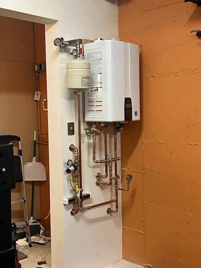 Plumbing technician inspecting water heater connections in Half Moon